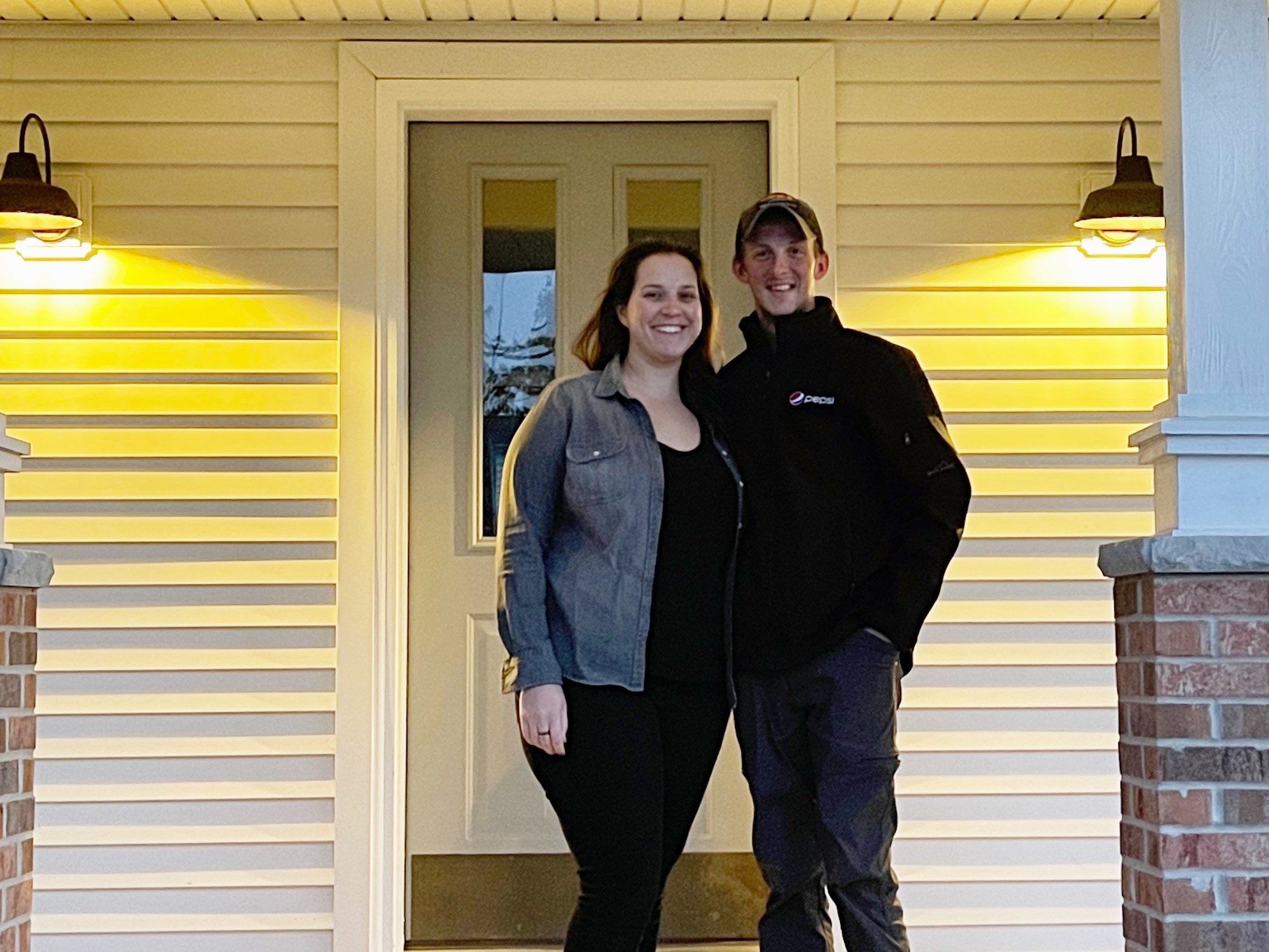 Two people standing on the front porch of a house